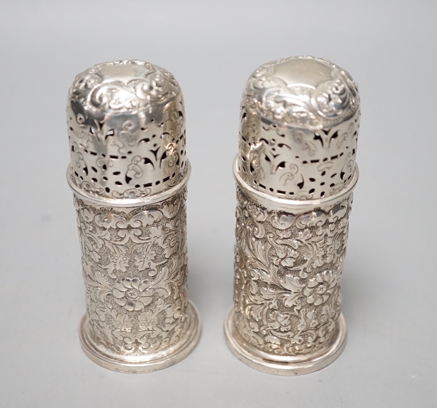 A pair of late Victorian embossed silver small lighthouse pepperettes, Horace Woodward & Co, London, 1895, 10.3cm, 156 grams.